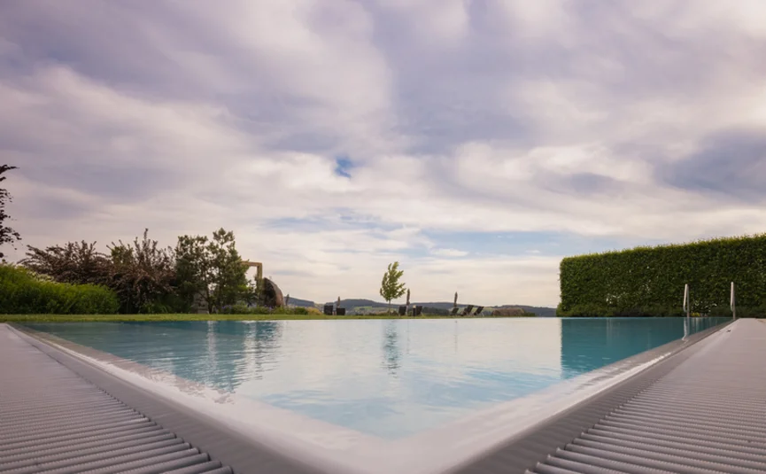 Blick auf einen Infinity-Pool mit bewölktem Himmel und Landschaft im Hintergrund