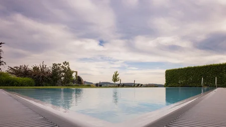 Neue Gravelbike Holidays Hotels 2026 © Detail Nicole Schaller Blick auf einen Infinity-Pool mit bewölktem Himmel und Landschaft im Hintergrund