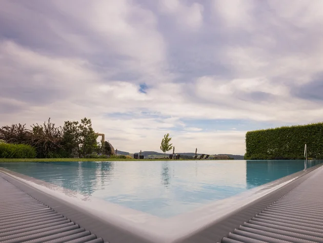 Blick auf einen Infinity-Pool mit bewölktem Himmel und Landschaft im Hintergrund