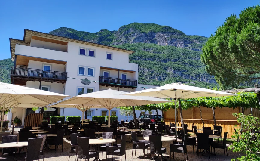 Leere Terrasse eines Cafés vor einem weißen Haus und Bergen im Hintergrund