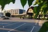 Hotel building with parking lot framed by green leaves in sunset light