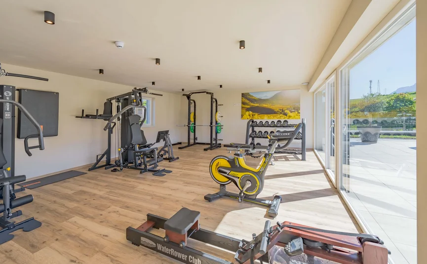Bright gym with rowing machine, exercise bike, weights, and large windows
