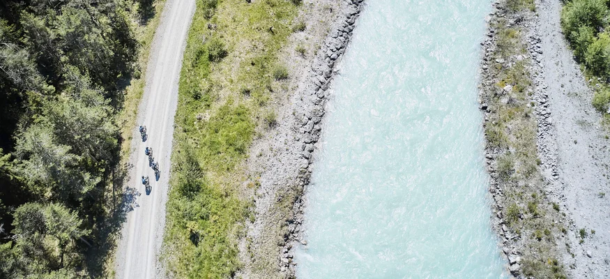 Draufsicht auf Radfahrer auf Waldweg neben hellem Fluss