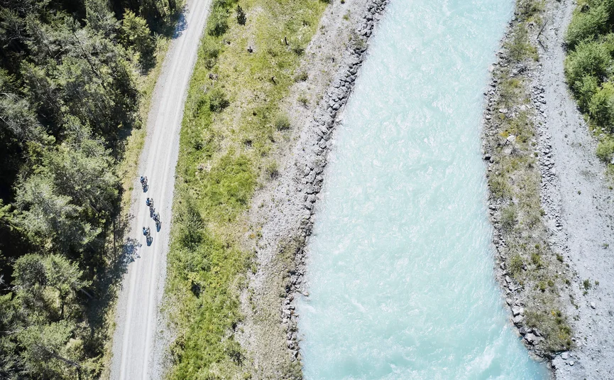 Draufsicht auf Radfahrer auf Waldweg neben hellem Fluss