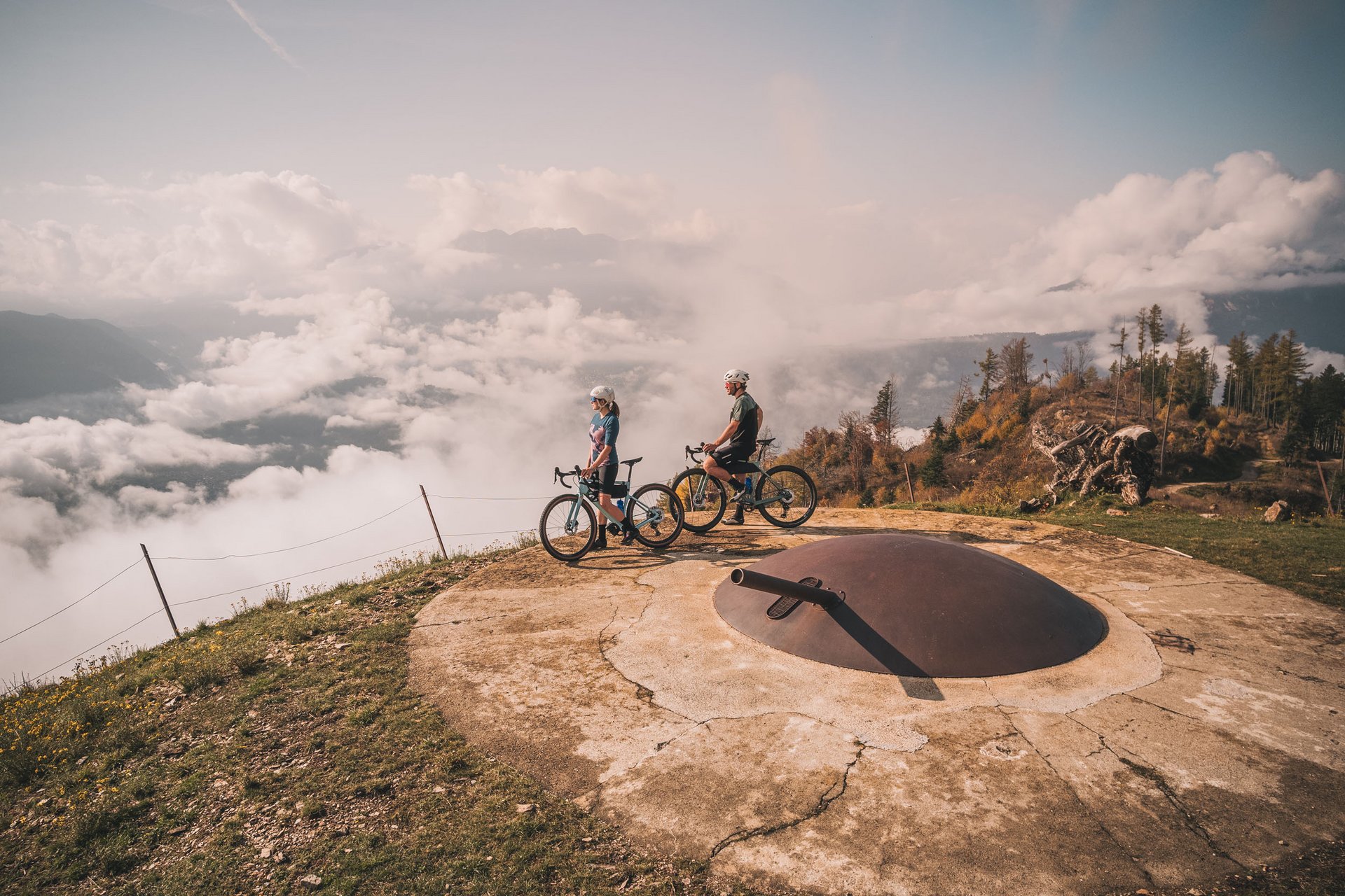 Gravelbike Holidays © Andrea Acler Zwei Radfahrer auf Berg mit altem Militärbunker und Nebel im Tal