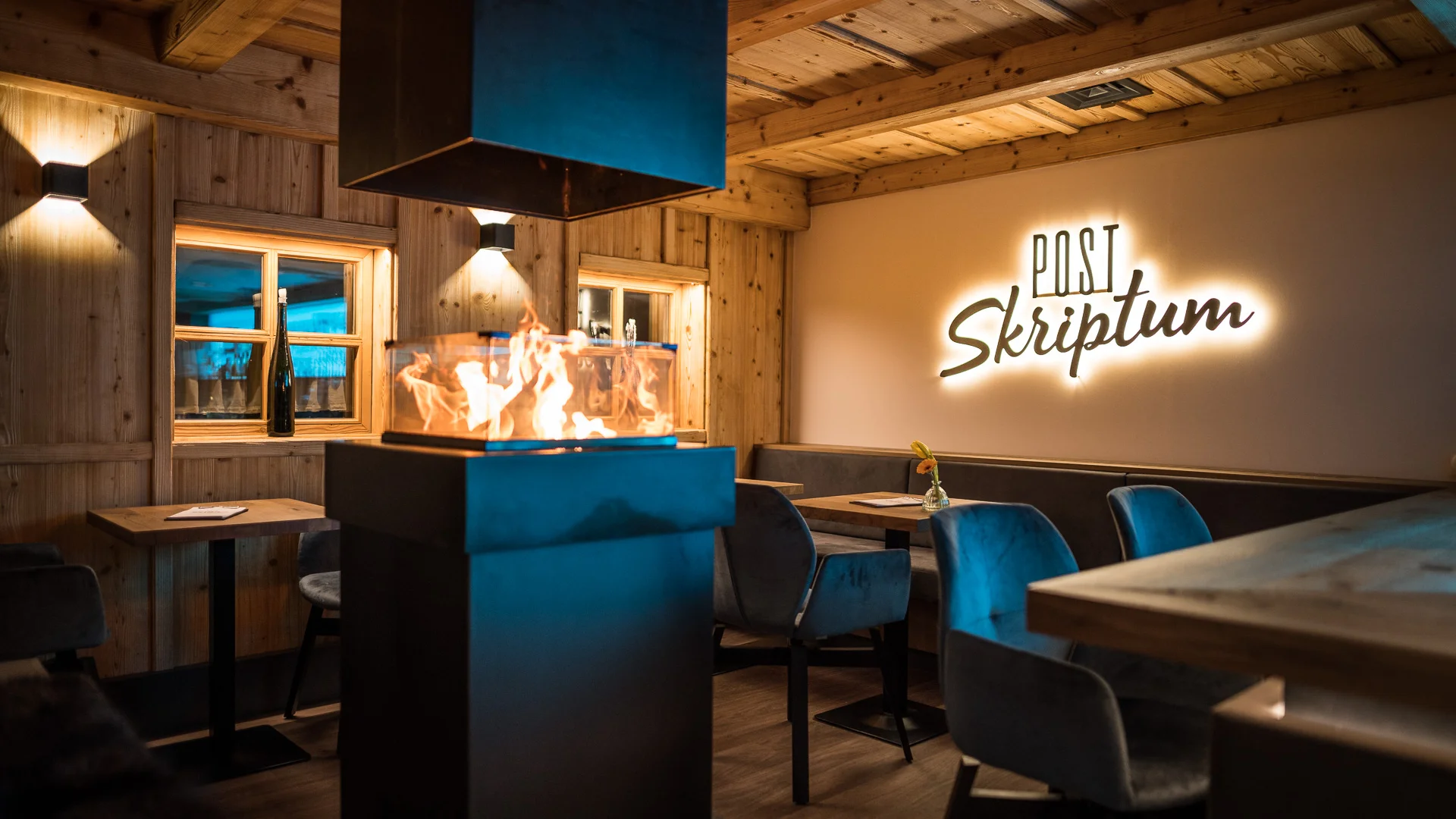Gemütlicher Holzraum mit modernem Kamin und beleuchtetem Schriftzug Post Skriptum