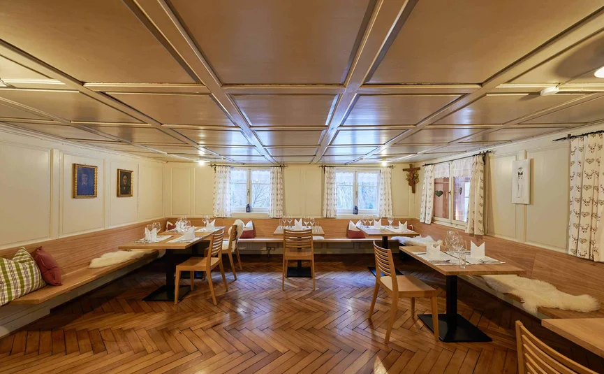 Gemütlicher Gastraum mit Holztischen und Fenstern mit Gardinen