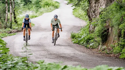 Zwei Radfahrer fahren auf einem Waldweg bergauf
