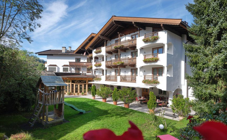 Hotelgebäude mit Balkonen und Spielplatz im Garten
