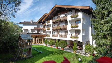 Hotelgebäude mit Balkonen und Spielplatz im Garten