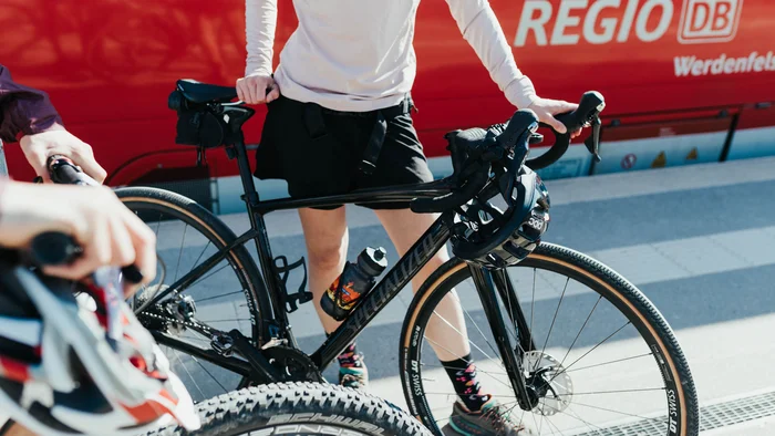 5 Tipps fürs Graveln in Oberbayern © Elisabeth Kellerer Person mit Rennrad vor rotem Regio DB Zug