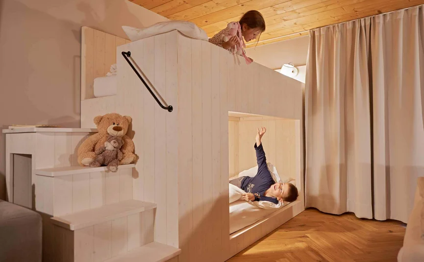 Kinder spielen in einem Etagenbett aus Holz in einem gemütlichen Raum