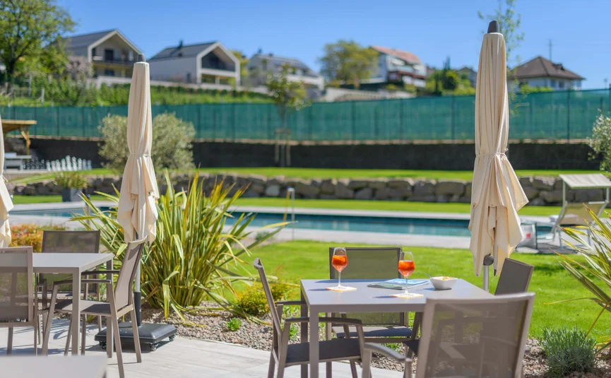 Outdoor seating with table and chairs by pool with closed umbrellas