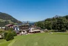 Mountain hotel with solar panels surrounded by meadows and mountains under clear sky