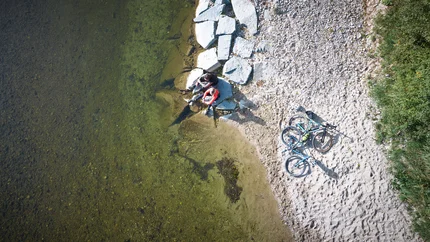 Zwei Radfahrer sitzen am Ufer neben zwei Fahrrädern