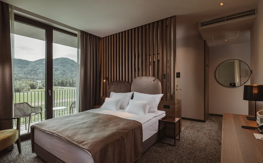 Modernes Hotelzimmer mit Doppelbett und Balkon mit Bergblick