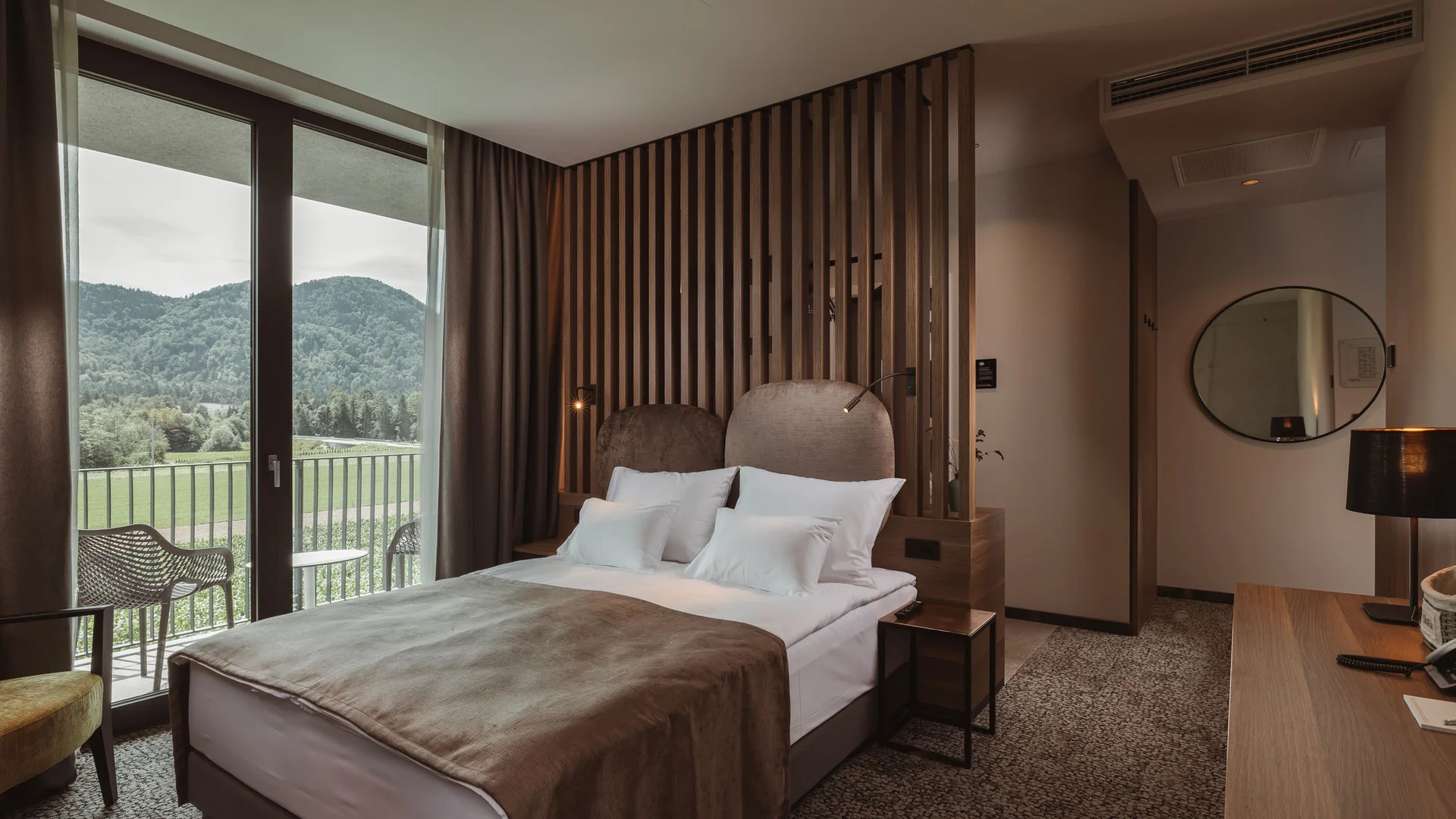Modernes Hotelzimmer mit Doppelbett und Balkon mit Bergblick
