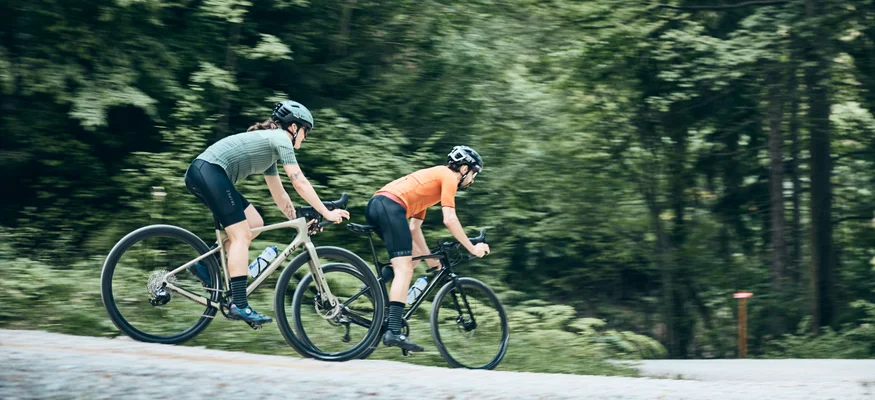 Zwei Radfahrer fahren auf einem Waldweg mit grünem Hintergrund
