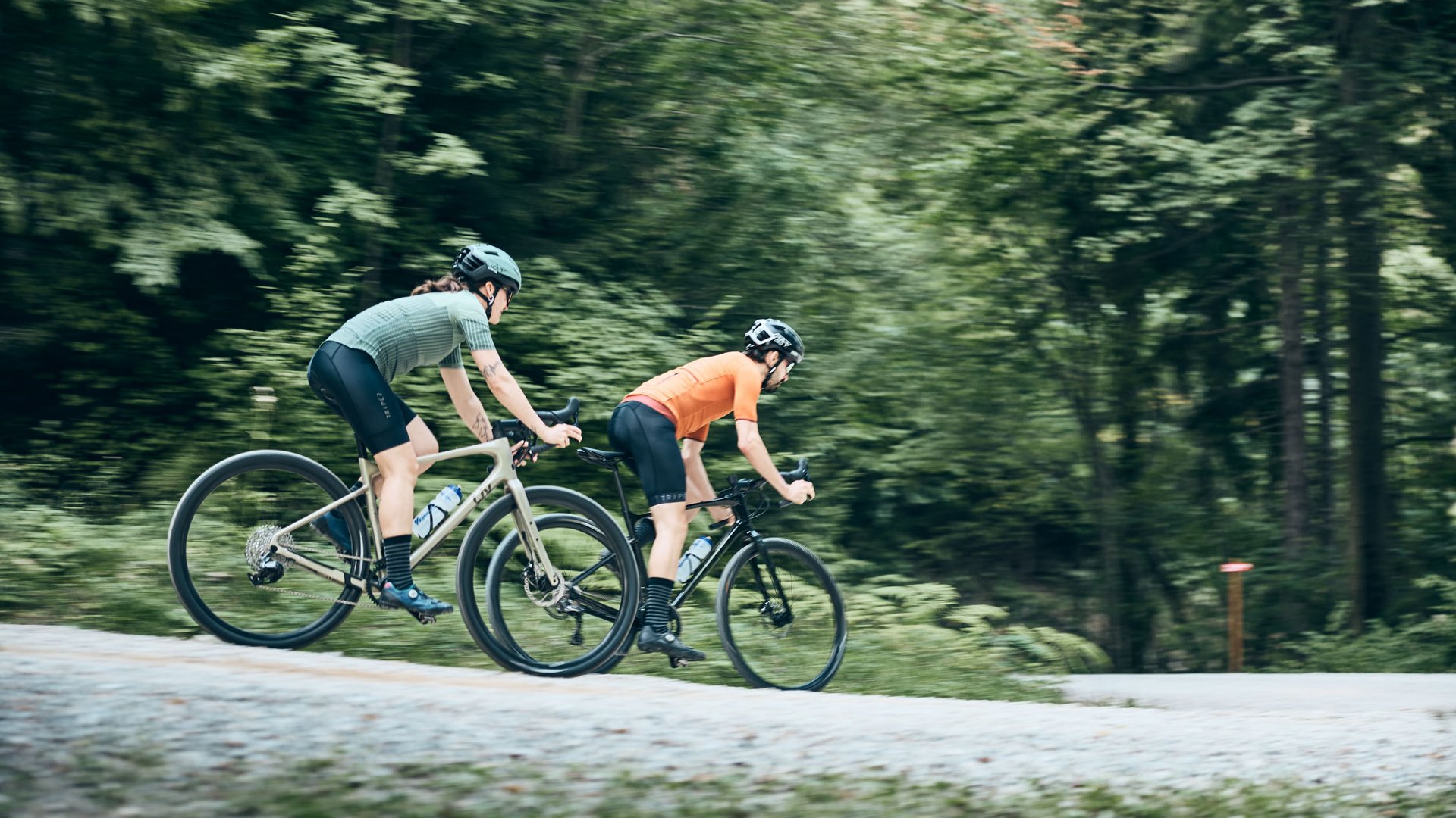 Zwei Radfahrer fahren auf einem Waldweg mit grünem Hintergrund