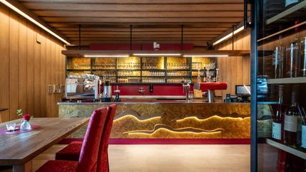 Modern bar area with wood paneling and red upholstered chairs