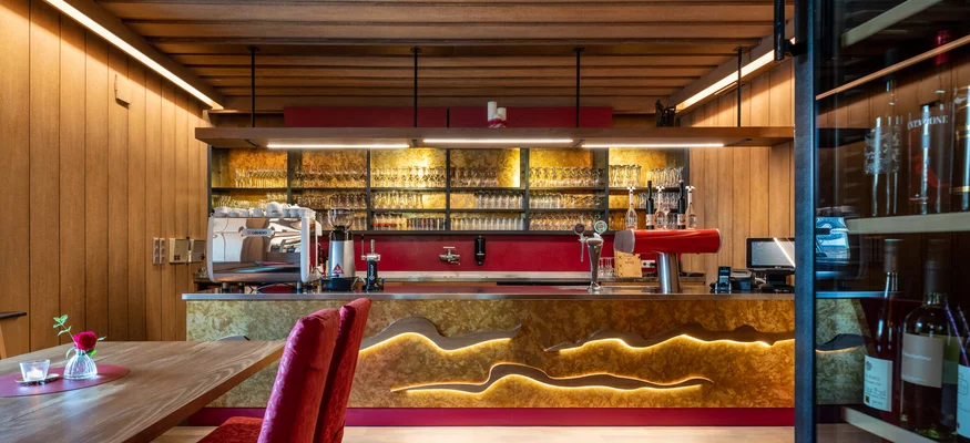 Moderner Barbereich mit Holzvertäfelung und roten Sitzstühlen