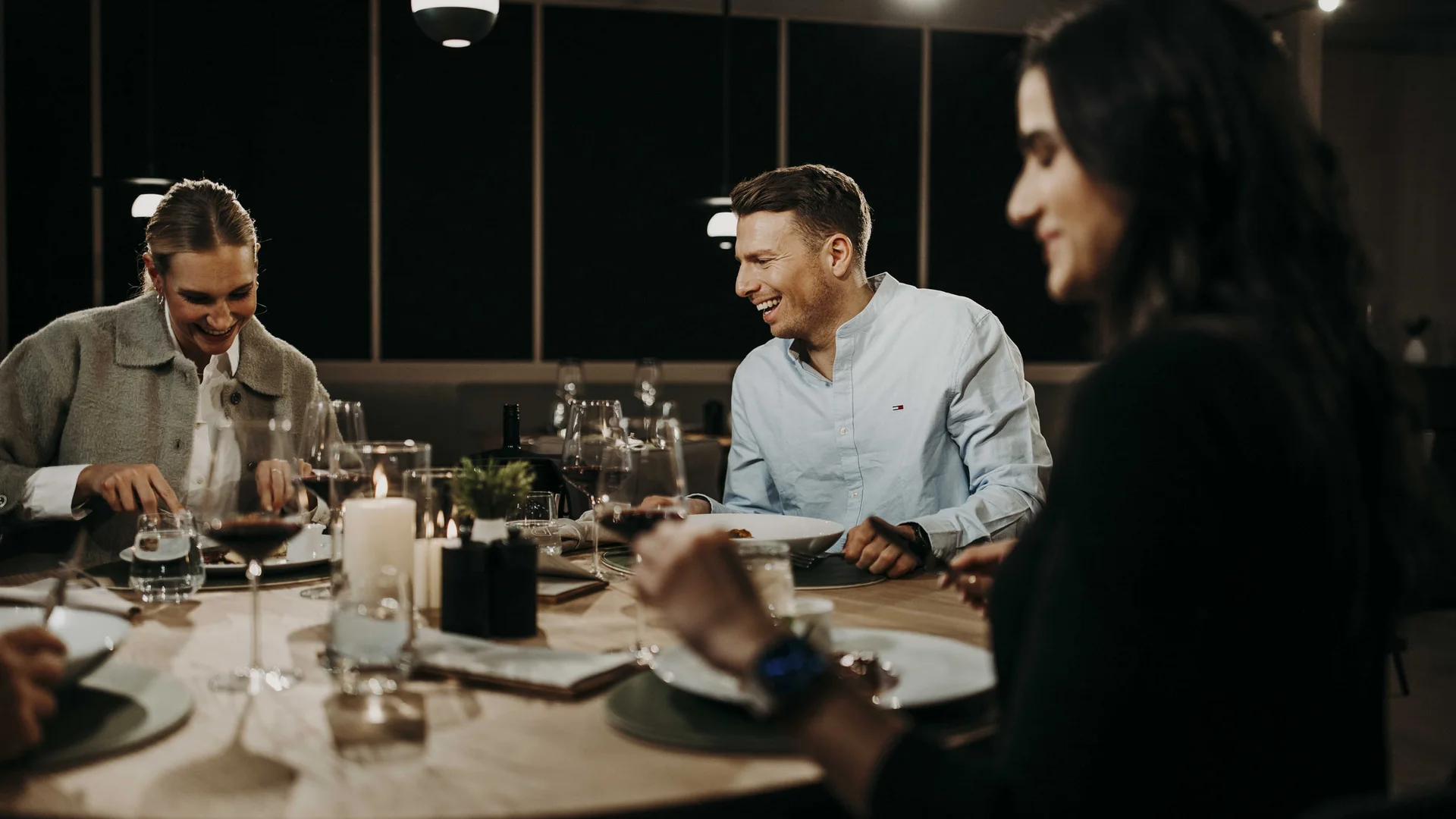 Drei Menschen genießen gemeinsames Abendessen in gemütlicher Atmosphäre