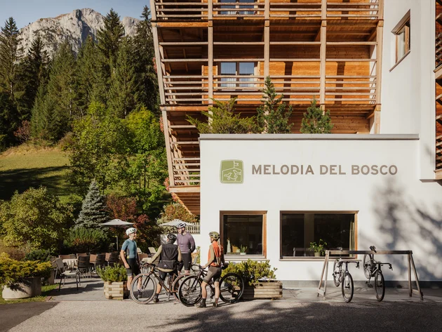 5 Gravelbike-Touren in Alta Badia, die du gefahren haben solltest © Alex Moling Fahrradfahrer stehen vor dem Hotel Melodia del Bosco in alpiner Umgebung