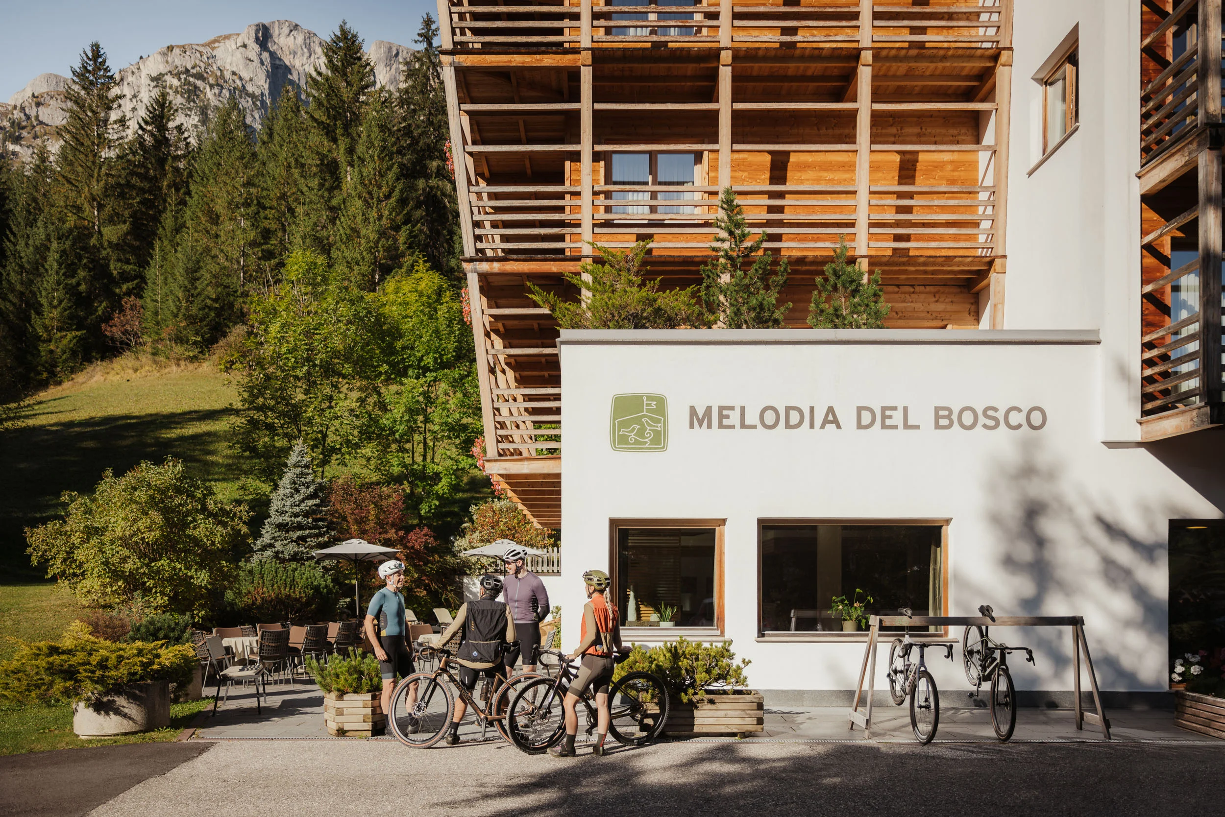 Cyclists standing outside Melodia del Bosco hotel in a mountain setting