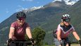 Zwei Frauen radeln auf einem Weg mit Bergen im Hintergrund