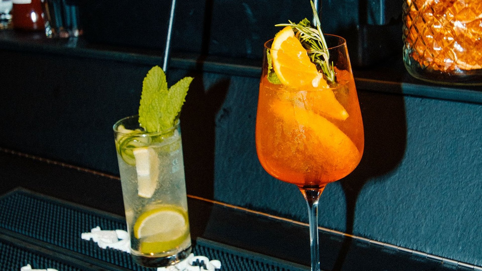 Zwei bunte Cocktails an einer Bar mit Früchten und Garnitur