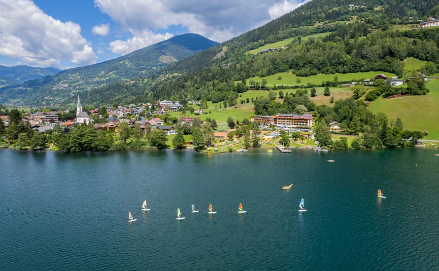 Gravel Badges Festival – 3 days of cycling and that autumnal feeling © Gert Perauer Sailboats on a lake with a village and green mountains in the background