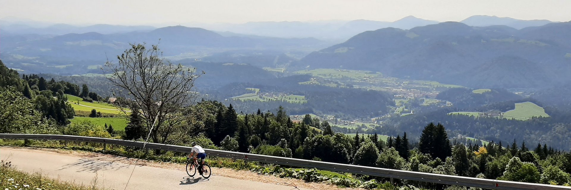 Cyclist on mountain road overlooking green valleys and mountains