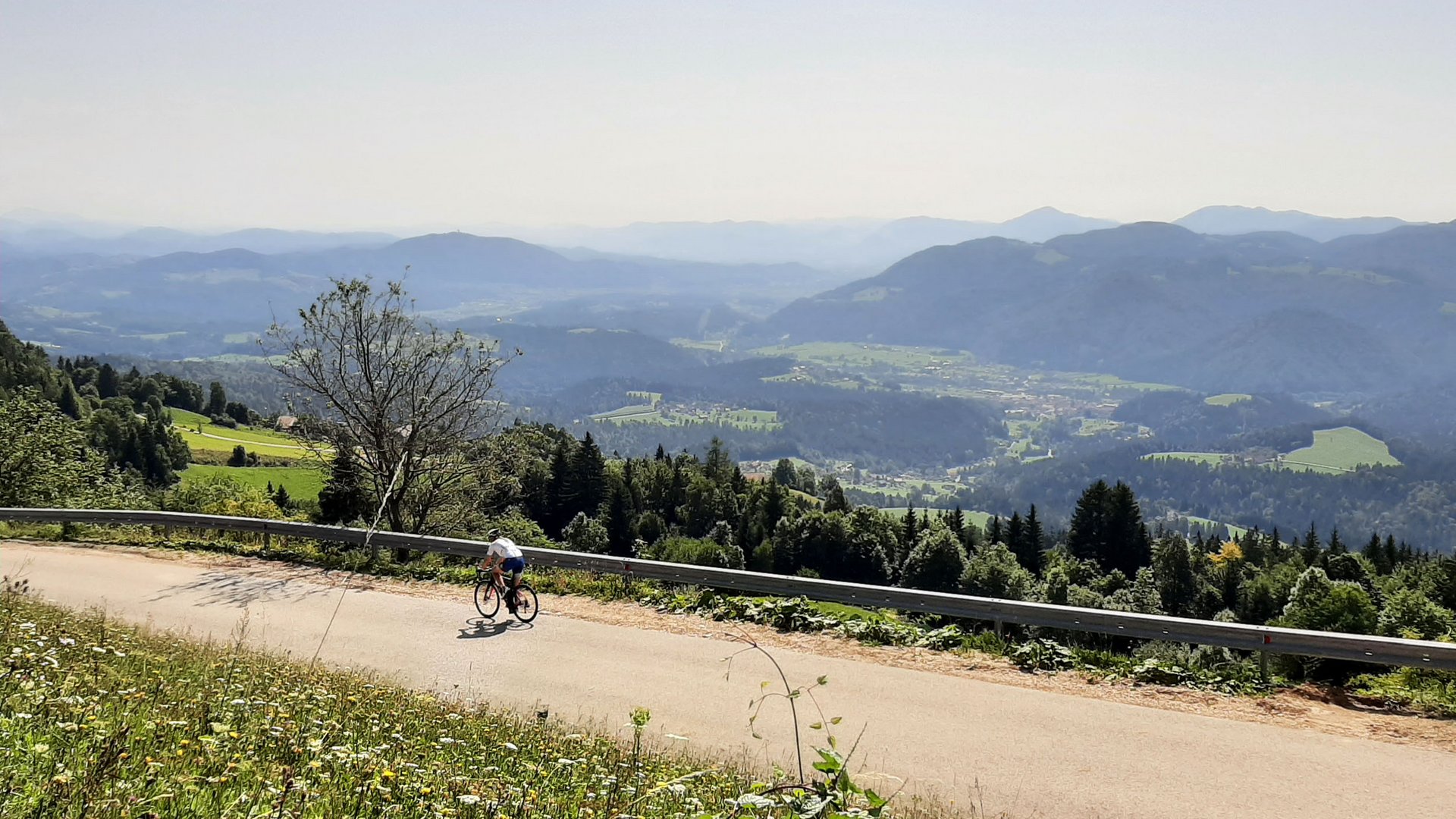 Radfahrer auf Bergstraße mit Blick auf grüne Täler und Berge