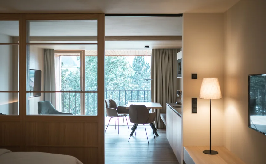 Modern living and dining area with large window overlooking trees
