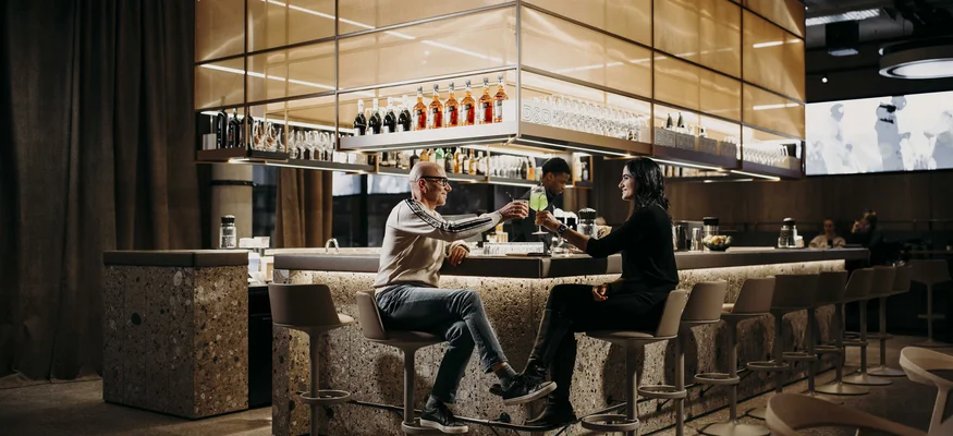 Dips&Drops - HOTEL · SPORTS · SPA · RESTAURANTS ****S © Matthias Warter Man and woman clinking cocktails at a modern bar