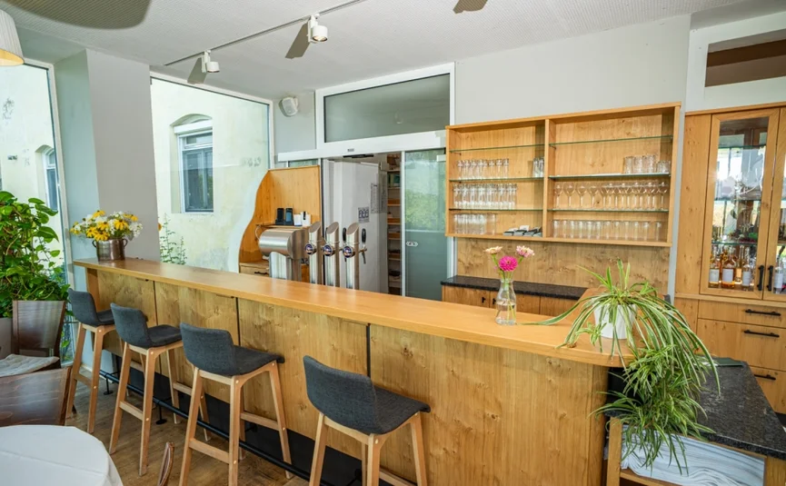 Moderner Holz-Barbereich mit Hockern und Glasregal in hellem Raum