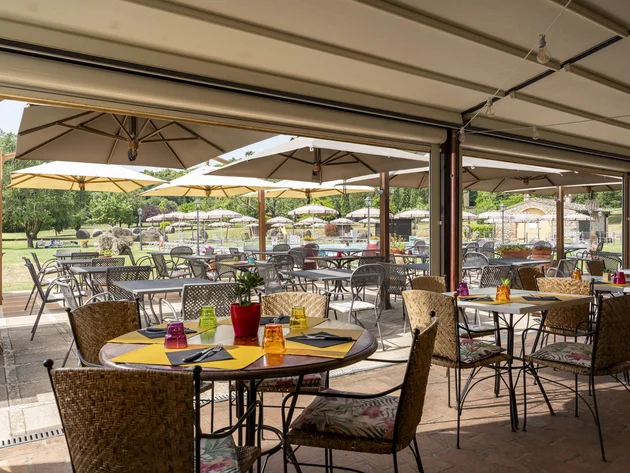 Gravelbiken in der Toskana © Hotel Casolare Le Terre Rosse Sonnige Außenterrasse mit Tischen, Stühlen und großen Sonnenschirmen