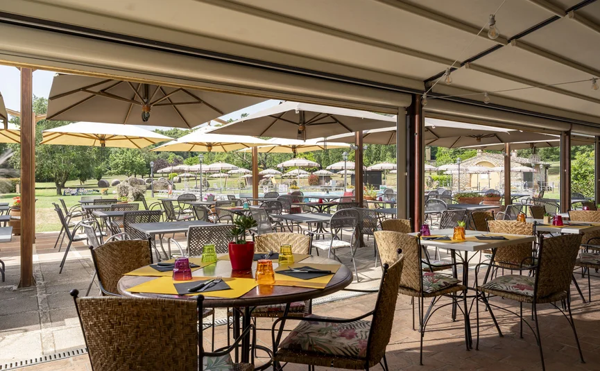 Sunny outdoor terrace with tables, chairs, and large umbrellas