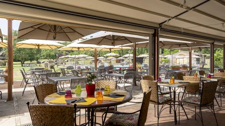 Gravelbiken in der Toskana © Hotel Casolare Le Terre Rosse Sonnige Außenterrasse mit Tischen, Stühlen und großen Sonnenschirmen