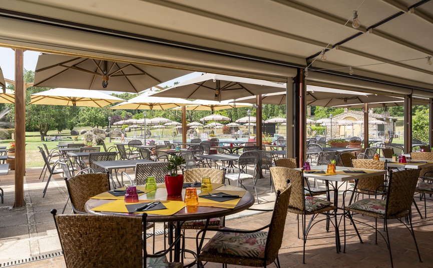 Hotel & Restaurant Casolare Le Terre Rosse ***S © Hotel Casolare Le Terre Rosse Sonnige Außenterrasse mit Tischen, Stühlen und großen Sonnenschirmen