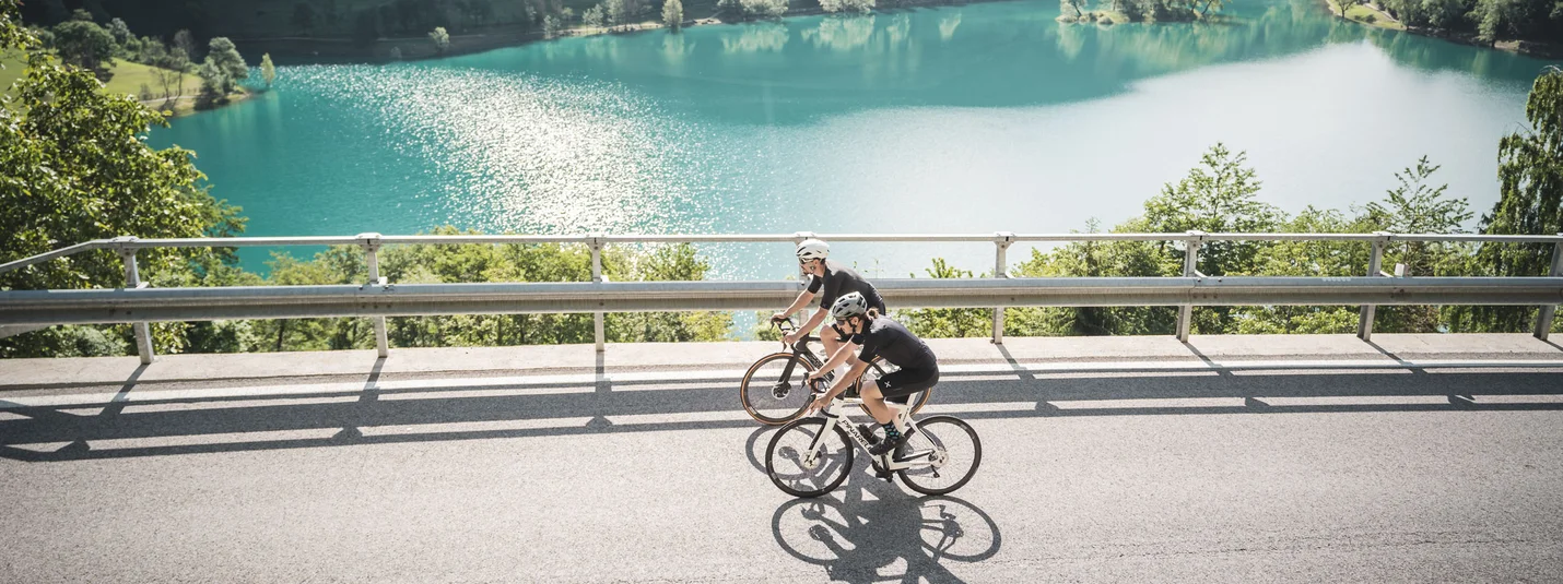 Lago di Tenno © APT Garda Dolomiti Two cyclists riding by a lake in a mountainous landscape