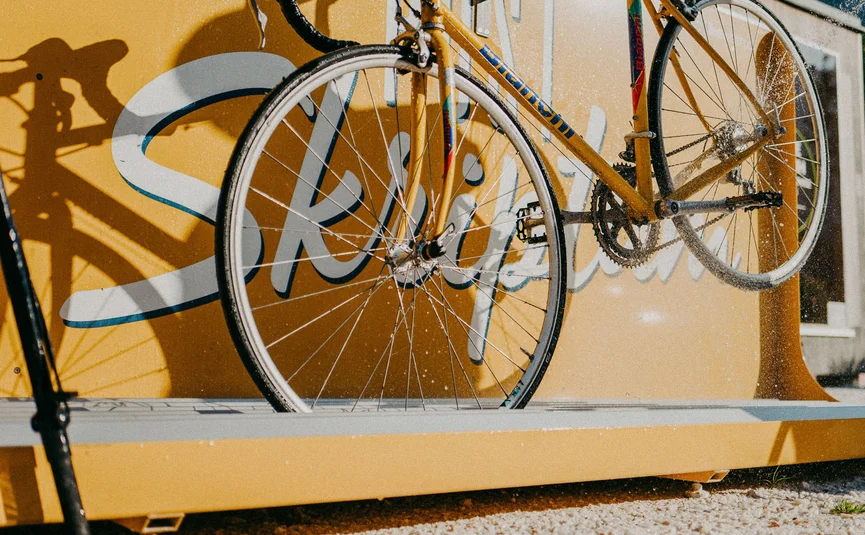 Altes gelbes Rennrad vor gelber Wand bei Sonnenschein