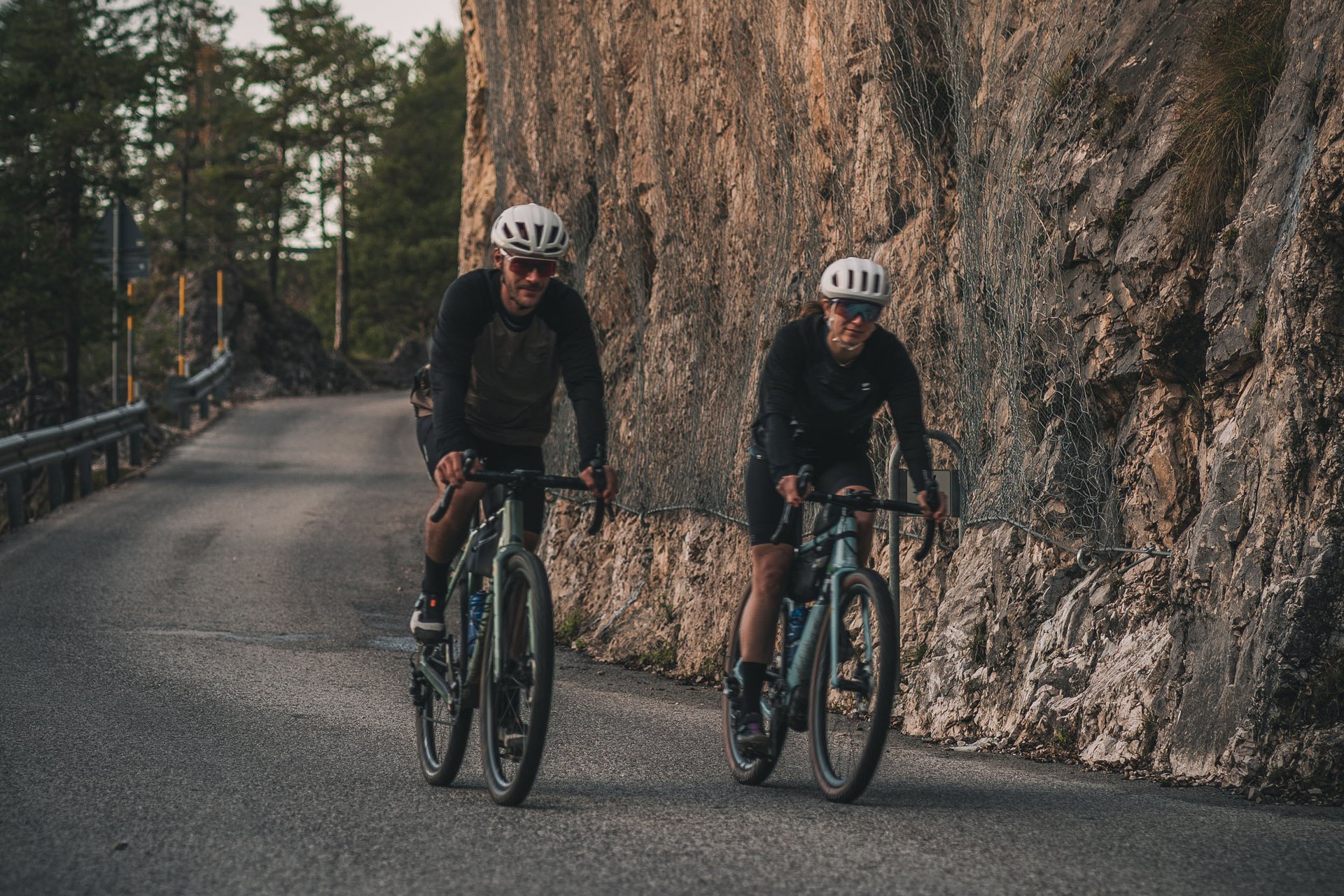 Zwei Radfahrer fahren auf einer Bergstraße neben einer Felswand