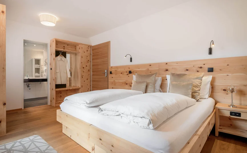 Zimmer mit Doppelbett, Holzmöbeln und Blick ins Bad