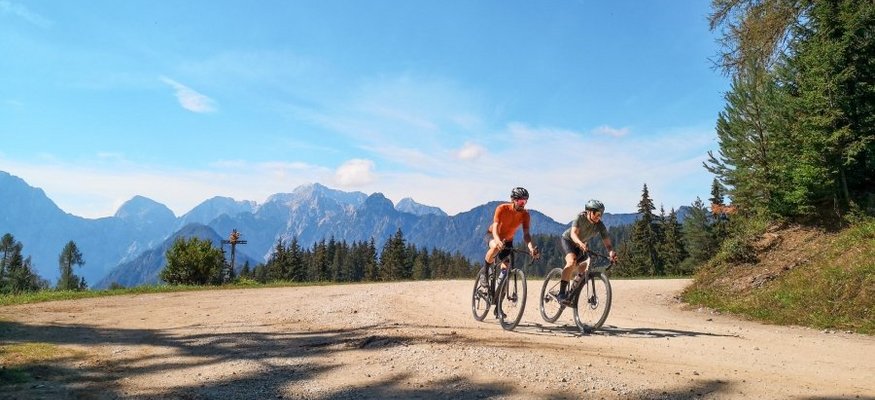 Savinja Tal © Tobias Köhler Zwei Radfahrer auf einem Waldweg vor Bergkulisse bei klarem Himmel