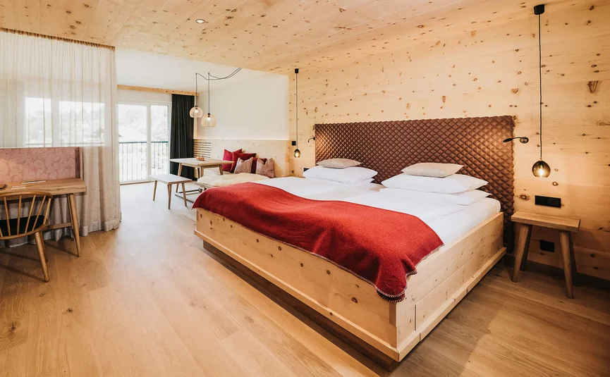 Bright hotel room with wooden furniture, double bed and seating area