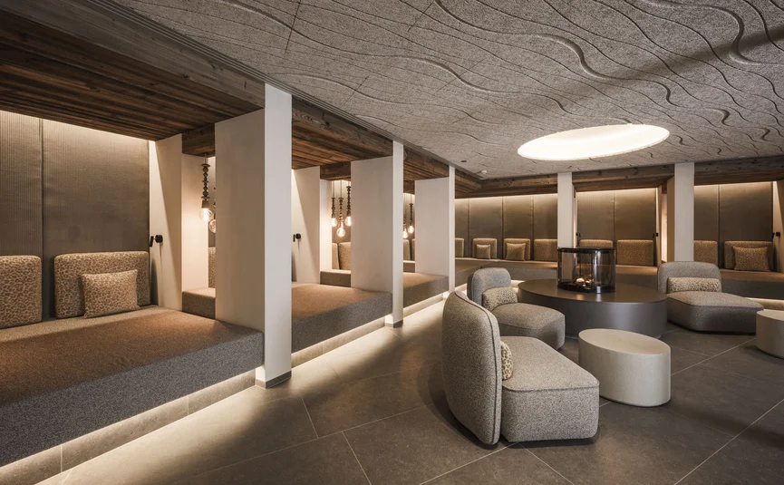 Modern lobby area with seating niches, armchairs, and a round ceiling light