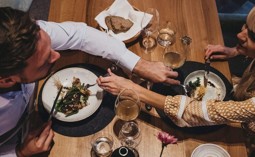 Couple sharing food at dinner table with wine glasses