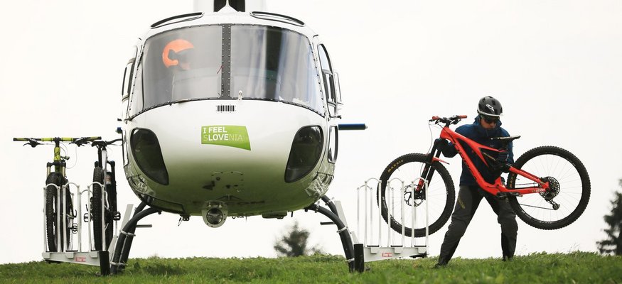 Hubschrauber mit Fahrrädern auf einer Wiese, eine Person trägt ein Fahrrad