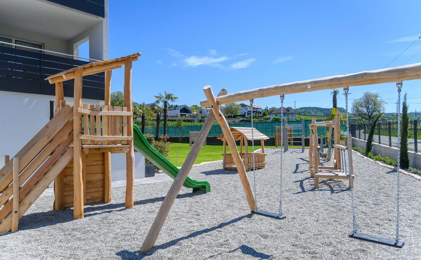 Children's playground with wooden swings and slide under a clear sky